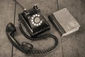 Retro black telephone and book on old oak wooden table. Vintage style sepia photo Royalty Free Stock Photo