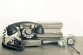 Retro black telephone and books, clock, dried flower on old oak wooden table. Vintage style sepia photo Royalty Free Stock Photo