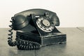 Retro black telephone on old oak wooden table. Vintage style sepia photo Royalty Free Stock Photo