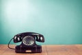 Retro black telephone on wooden table in front mint blue background. Vintage style photo