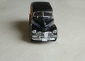 Retro black toy car on gray striped surface. Model of classic vintage sport car with shadows and partly soft focus. Front view of