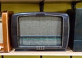 Retro broadcast radio receiver on wooden shelf against yellow background