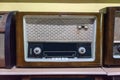 Retro broadcast radio receiver on wooden shelf against yellow background