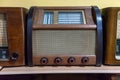 Retro broadcast radio receiver on wooden shelf against yellow background