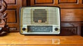 Retro broadcast radio receiver with green eye light on wooden table