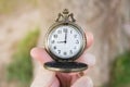 Retro bronze opened pocket watch in human fingers, 9 o`clock on the dial. Close-up