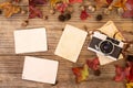 Retro camera and empty old instant paper photo album on wood table with maple leaves in autumn Royalty Free Stock Photo