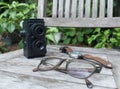 Retro camera, eyeglasses and watch on wooden background