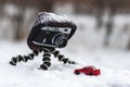 Retro camera with a hat is standing on a tripod on a winter blurred background. The model of red car Royalty Free Stock Photo