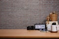 Retro camera, pencil holder, coffee cup and smart phone on wooden table with brick wall Royalty Free Stock Photo