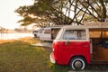 Retro camper van parked in campground on lakeside in the sunset