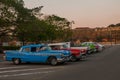 Retro cars parked, waiting for tourists to walk around the city, in the distance the fortress Fortaleza de San Carlos de La Cabana