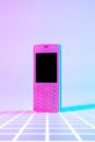 Retro cell phone vintage concept. White old mobile telephone in neon pink blue light. Retro wave. Pop art. minimal idea Royalty Free Stock Photo