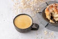 Retro coffee cup and bitten fresh baked cinnamon bun roll on metal baking rack with dried flowers on grunge stone table background Royalty Free Stock Photo