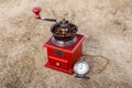 Retro coffee grinder with coffee beans and vintage bronze pocket watch, 9 o`clock. Still life on dry ground Royalty Free Stock Photo