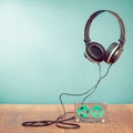 Retro compact cassette with rolls and headphones front mint blue background. Vintage style filtered conceptual photo Royalty Free Stock Photo