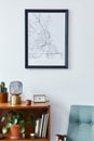 Retro composition of living room interior with mock up poster map, wooden shelf, books, lamp, armchair, plant, clock, cacti.
