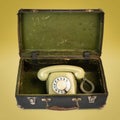 Retro dial phone in an old suitcase isolated on the yellow background Royalty Free Stock Photo