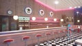 Retro diner interior with a tile floor, neon illumination, jukebox and art deco style bar stools. 3d illustration Royalty Free Stock Photo