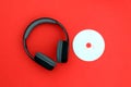 A retro disc with wireless headphones lies on a red background. Royalty Free Stock Photo