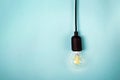 Retro electric light bulb with cord isolated on turquoise color background with copy space.