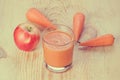 Retro filtered glass of homemade juice, apple and carrot on wooden board