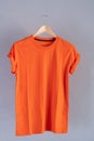 Retro fold orange cotton T-Shirt clothes mock up template on grunge white wood background concept for retail dress shop backdrop,