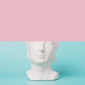 Retro head sculpture against the two tone pastel background.