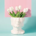 Retro head sculpture with tulip flowers on a pastel blue pink background.