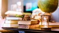 Retro hourglass, blur stack of old books and world desk globe on wooden table