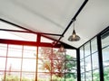 Retro industrial style chrome ceiling lamp with light bulb hanging on black bar in glass house Royalty Free Stock Photo