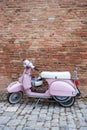 Retro Italian Vespa motorcycle parked near bricks wall