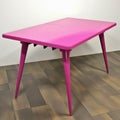 A retro magenta dining table with four spindlestyle legs. Trendy color of 2023 Viva Magenta.. AI generation