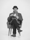 Retro man, gentlmen and detective with serious look sitting on chair and drinking coffee. Retro vintage fashion, job Royalty Free Stock Photo