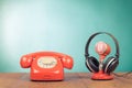 Retro microphone, headphones and telephone on wooden table front mint blue background. Vintage style filtered photo Royalty Free Stock Photo