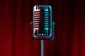 Retro microphone of metallic color on a background of red wings, red curtains. Concept of stand-up performance, show, humor,