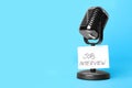 Retro microphone and reminder note with words JOB INTERVIEW on blue background, space for text Royalty Free Stock Photo