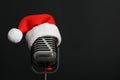 Retro microphone with Santa hat on black background, space for text. Christmas music Royalty Free Stock Photo