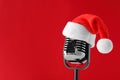Retro microphone with Santa hat on red background, space for text. Christmas music Royalty Free Stock Photo