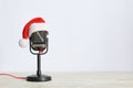 Retro microphone with Santa hat on wooden table against white background, space for text. Christmas music Royalty Free Stock Photo