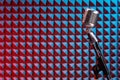 Retro microphone standing on a stand, with acoustic foam panel at background Royalty Free Stock Photo