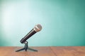 Retro microphone on wooden table front mint blue background. Vintage style photo