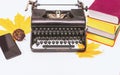 Retro and modern writer gadgets: mobile phone, old typewriter, stack of books and yellow dry leaves Royalty Free Stock Photo