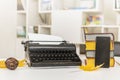 Retro and modern writer gadgets: mobile phone, old typewriter, stack of books and yellow dry leaves