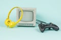 Retro monitor, yellow headphones and a game console on a blue background