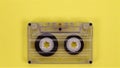 Retro music compact cassette reeling tape on yellow