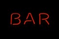 Retro neon sign with the word bar. Vintage electric symbol. Burning a pointer to a black wall in a club, bar or cafe. Design