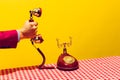 Retro objects, pop art photography. Female hand holding handset of vintage phone isolated on bright yellow background Royalty Free Stock Photo