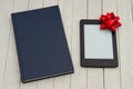 Retro old blue book on a desk with an ereader with gift bow