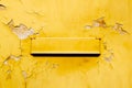 Retro old yellow mailbox vintage postal box mounted on a cracked, grunge and peeling yellow wall Royalty Free Stock Photo